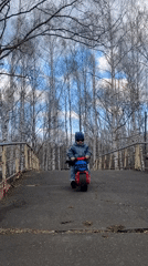 Children ride toy motorcycles on bridge in Chaikovsky