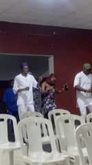 Group in white outfits, purple hats gather for indoor event