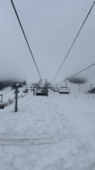 Foggy day skiing captured from moving chairlift at resort
