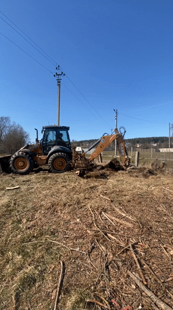 Backhoe clears roots and debris in Belarus field