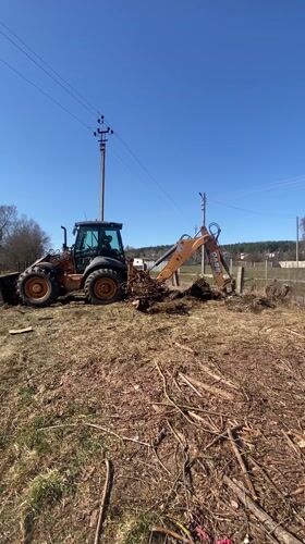 Backhoe clears roots and debris in Belarus field