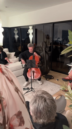 Late-night cello practice in an LA apartment with a city view