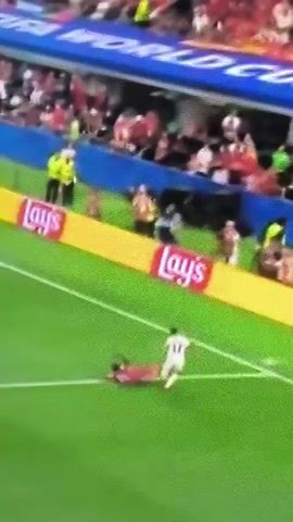 The video shows a soccer match. A player in a red uniform is on the ground in the foreground. Another player in a white uniform with the number 12 on it is running past. The background shows a stadium with spectators. There are advertising banners around the field, including one for Lay's potato chips. A scoreboard shows the score of 0-0 between POR and ESP.