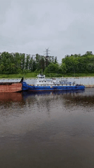 Tugboat pushes barge through Rybinsk river lock early morning