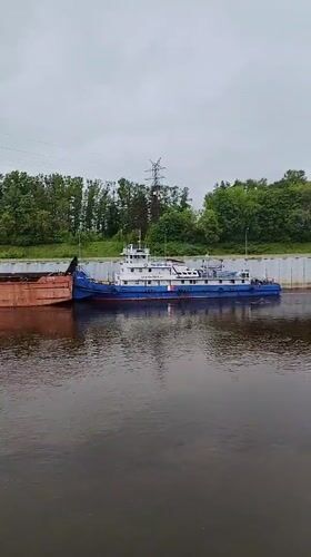 Tugboat pushes barge through Rybinsk river lock early morning