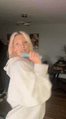 Woman dances and sings with microphone in London apartment