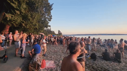 Sunset beach gathering with drumming, hula hooping, and ocean wading