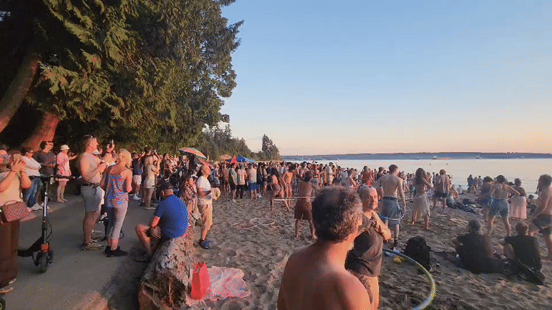 Sunset beach gathering with drumming, hula hooping, and ocean wading