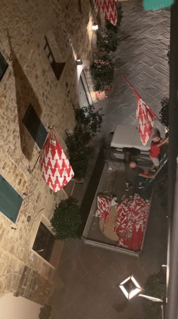 Night-before flag setup in San Quirico d'Orcia's stone streets