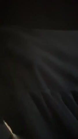 The video shows a person in a dark room pulling a white curtain to the side. The curtain is draped and wrinkled. A thin, vertical stripe of light is visible near the left edge of the frame.