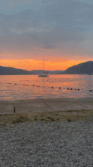 Sunset over Tivat bay with a catamaran on still water
