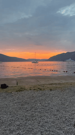 Sunset over Tivat bay with a catamaran on still water