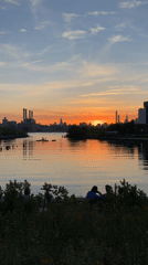 Couple watches sunset at NYC waterfront during golden hour