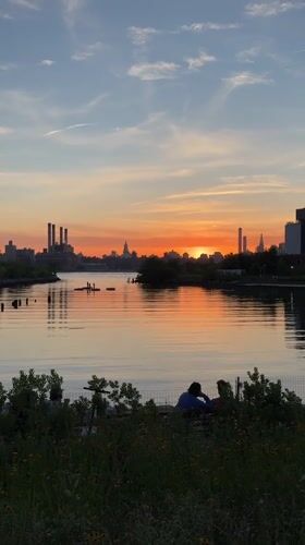 Couple watches sunset at NYC waterfront during golden hour