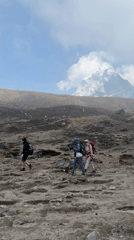 Three trekkers cross rocky terrain near Khumjung, Nepal