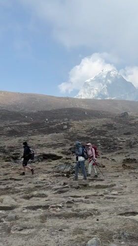 Three trekkers cross rocky terrain near Khumjung, Nepal