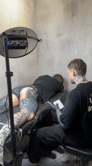 Tattoo artist works on client's leg in Moscow parlor