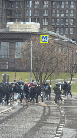 Pedestrians cross Moscow street during rainfall with umbrellas