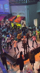 Colorful-wigged dancers perform on small public stage