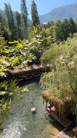 Riverside restaurant with thatched huts over clear water, Alanya