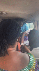 Vehicle passengers travel past golden statue during afternoon journey