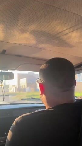 The video is filmed from inside a car, looking forward through the windshield and slightly to the right. Sunlight streams through the windshield, creating lens flares and bathing the interior in a warm glow. The ceiling of the car is visible at the top of the frame, appearing to be made of a perforated material. A man's head and shoulders are visible in the right side of the frame, from behind. He is wearing sunglasses and has dark hair. The dashboard of the car is visible below the windshield, with the word "LADA" clearly visible on the right side of the dashboard. Outside the car, buildings and vegetation are visible, suggesting a residential or suburban area. The time stamps indicate a short duration of four seconds.