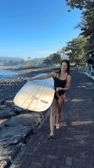 Surfer walks to ocean carrying board on brick path