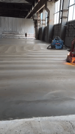 Ride-on trowels finishing a concrete floor in Riga warehouse