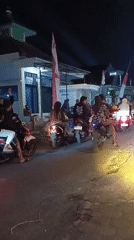 Nighttime motorcycle convoy through Indonesian streets amid national celebrations