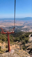 Ski lift descends a sunny green mountain slope