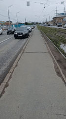 Izhevsk street life: trams, potholes, and puddles on a grey morning