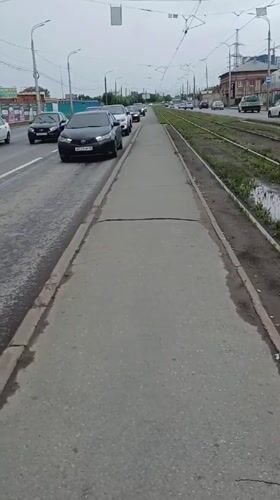 Izhevsk street life: trams, potholes, and puddles on a grey morning