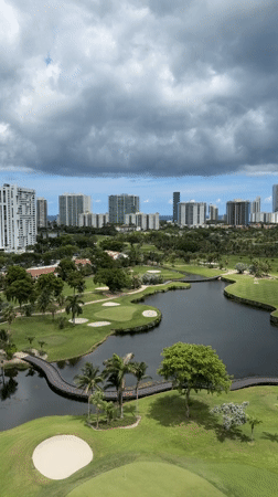 Drone footage over Aventura golf course with city skyline backdrop