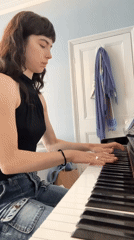 Woman plays piano at London home with orange cat present