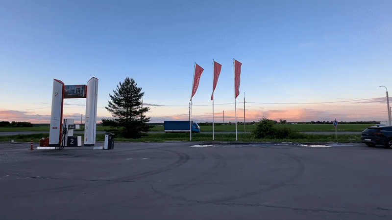 Woman takes playful selfies at Russian gas station during sunset