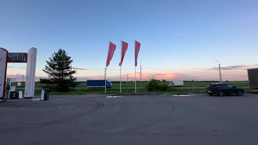 Woman takes playful selfies at Russian gas station during sunset
