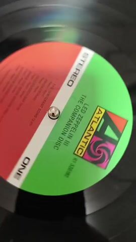 This video shows a close-up, spinning vinyl record. The record has a green and red label with white text. The label reads "ATLANTIC", "LED ZEPPELIN III", "THE COMPANION DISC", "ONE", and "STEREO". The record is on a turntable and the camera is focused on the label.