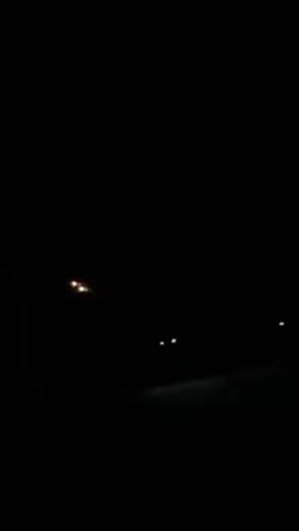 The video is recorded at night. A streetlight is visible, along with the headlights of a vehicle in the distance. The scene is dark.