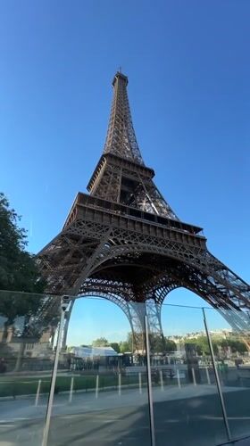 Eiffel Tower from below, reflected in a glass barrier