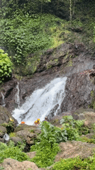 Group visits waterfall in safety gear near Rendang, Indonesia