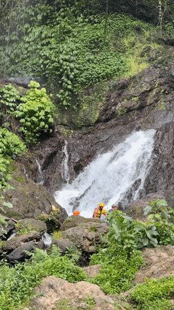 Group visits waterfall in safety gear near Rendang, Indonesia