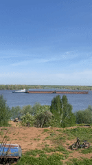 Tugboat tows barge across river in Ольховка, Russia