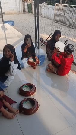 Kids practice hand drumming outdoors in Swarga Bara, Indonesia