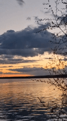 Woman photographs sunset over lake in Chaikovsky, Russia