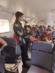 Man performs musical act on train with microphone
