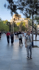 Pedestrians walk along tree-lined Barcelona street