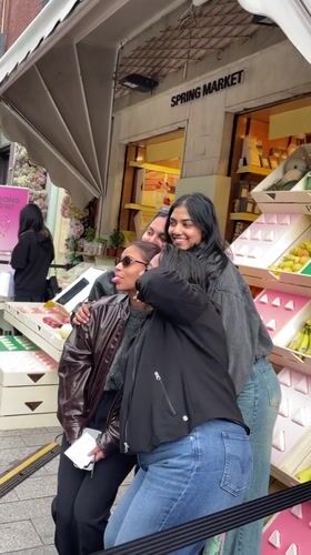 Women pose at Prada Spring Market display in Milan