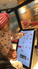 Child in pink Hello Kitty outfit uses KFC kiosk