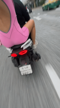 Pillion ride through Bangkok streets, pink outfit in frame