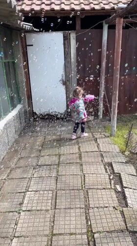 Child plays with bubble machine on Bulgarian patio